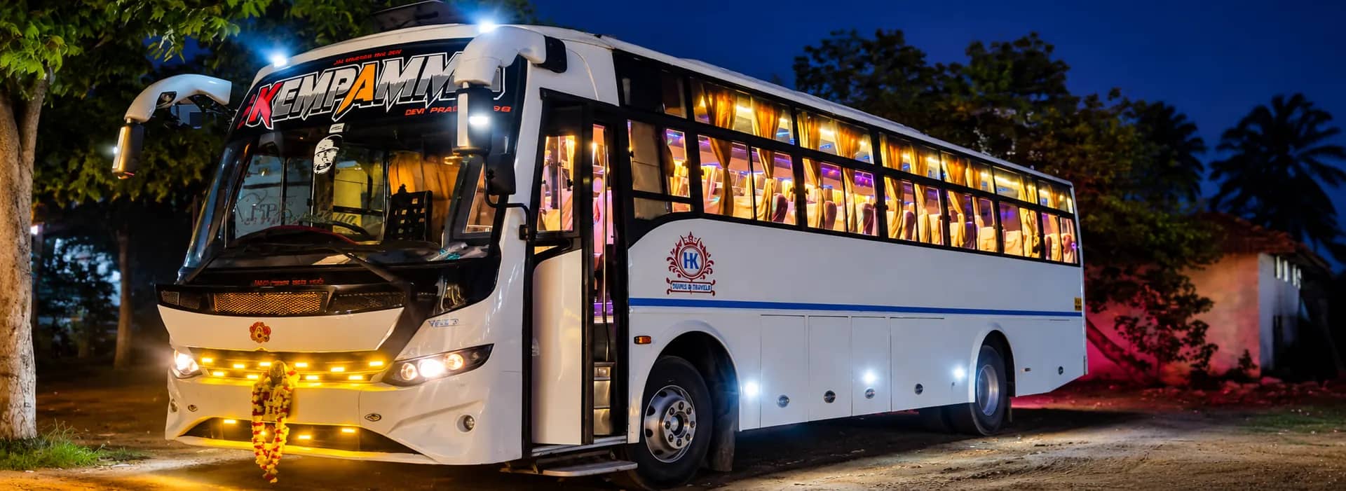 H K Tours and Travels luxury coach lit up at night in Bengaluru
